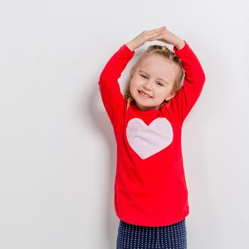 cute laughing little girl in red sweater with her arms folded