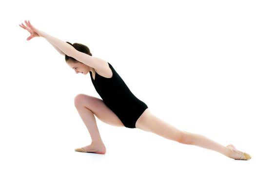 A girl gymnast performs an acrobatic element on the floor. The concept of childhood, sport, healthy lifestyle. Isolated on white background.