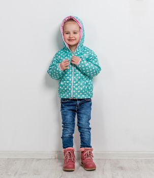 trendy lovely little girl in jeans, jacket and boots