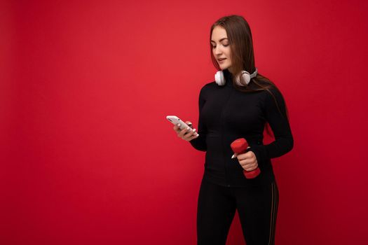 Beautiful young woman wearing casual clothes standing isolated over background surfing on the internet via phone looking at mobile screen.