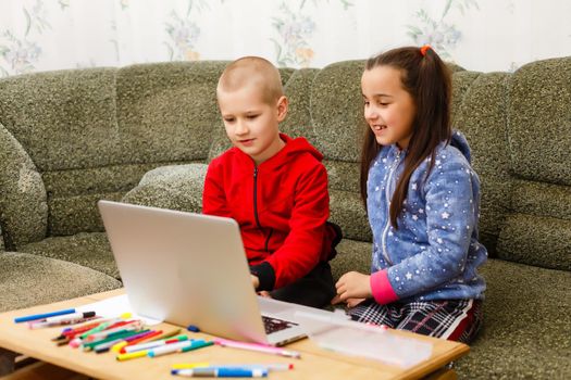 Distance learning online education. school boy and girl studying at home with laptop notebook and doing homework. Sitting at a table