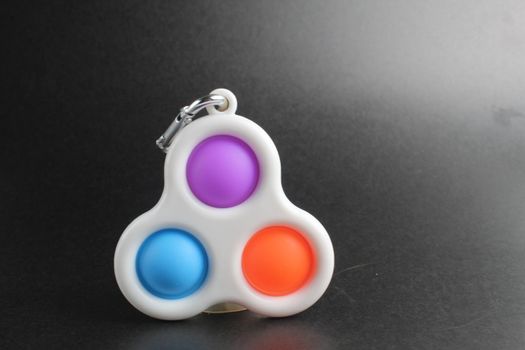 colorful antistress sensory toy fidget push pop it simle dimle on black background.