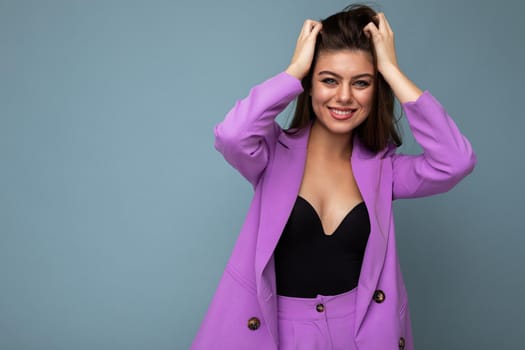 Young happy smiling brunette woman nice-looking attractive charming elegant fashionable wearing stylish suit with jacket isolated over blue background with copy space. Fun anf joy concept.