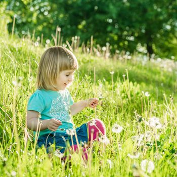 Happy little girl on the field with dandelions