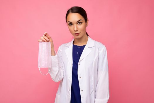Caucasian woman showing protection face mask isolated on pink background. Coronavirus or Covid-19 Concept.