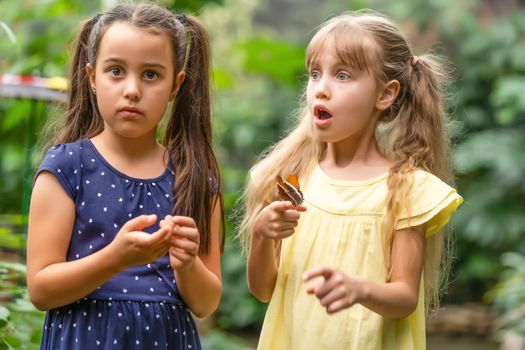 two little girls with butterflies in a greenhouse