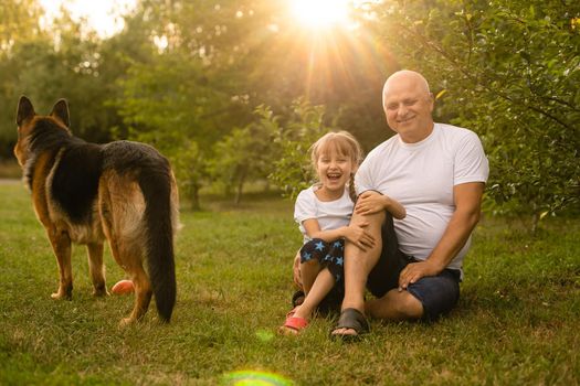Grandfather with granddaughter and a dog in the garden