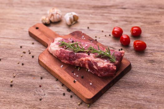 fresh raw meat for steak on wooden cutting board