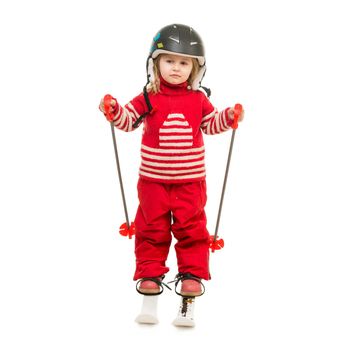 little girl in red ski suit standing on skis with ski poles and in helmet isolated on white background