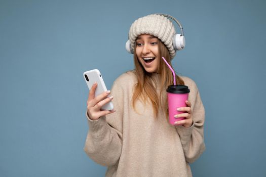 Photo of attractive crazy amazed surprised young woman wearing casual stylish clothes standing isolated over background with copy space holding and using mobile phone looking at gadjet screen.