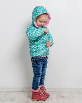 little girl fastening her blue dotted jacket