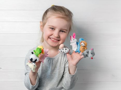 Lovely small girl with doll puppets on her hands, smiling and playing