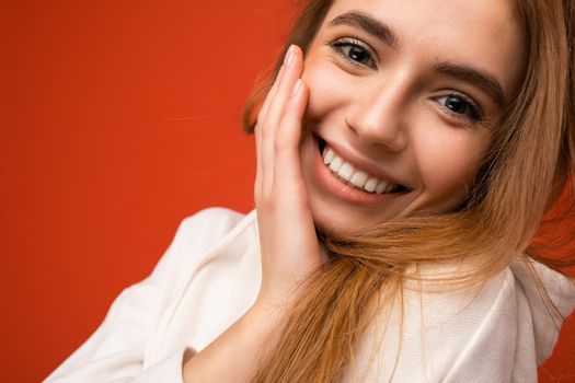 Closeup portrait of young smiling beautiful dark blonde woman with sincere emotions isolated on background wall with copy space wearing casual white hoodie. Positive concept.
