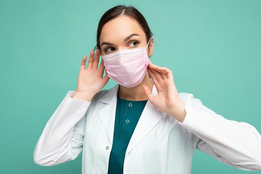 Young beautiful woman in reusable virus protective mask on face against coronavirus isolated on the blue background wall.