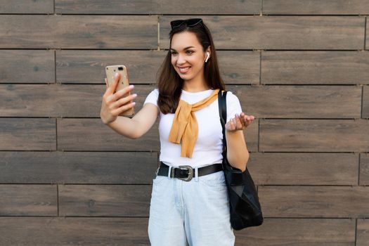 side-profile Photo of beautiful young woman wearing casual clothes standing in the street having communication via mobile phone looking at smartphone and having fun and good mood.