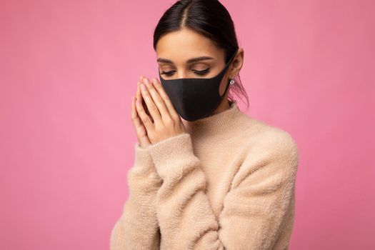 Brunette woman wearing an anti virus protection mask to prevent others from corona COVID-19 and SARS cov 2 infection isolated on pink background.