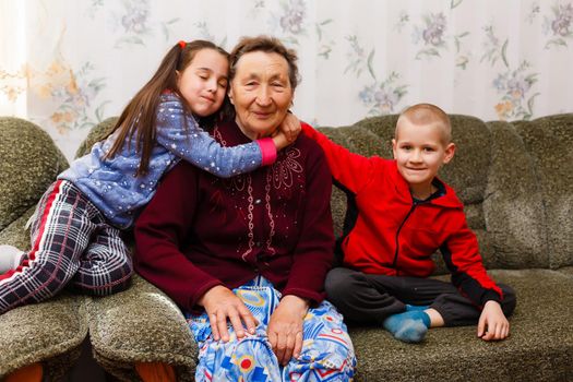 Grown up adult smiling grandchildren embraces elderly grandmother glad to see missing her, visit of loving relatives enjoy communication, cuddle as symbol of connection, love and support concept