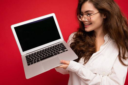 Close-up portrait of smiling Beautiful smiling happy young woman holding computer laptop looking at netbook having fun wearing casual smart clothes isolated over wall background. mock up