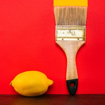 lemon and paint brush on red background.