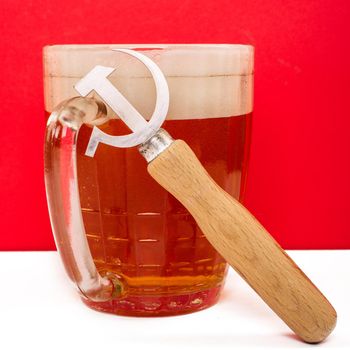 Retro opener from the Soviet era in the shape of a sickle and hammer next to a beer on a red background.