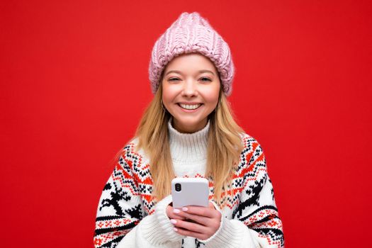 portrait Photo shot of attractive positive good looking young woman wearing casual stylish outfit poising isolated on background with empty space holding in hand and using mobile phone messaging sms looking at camera.