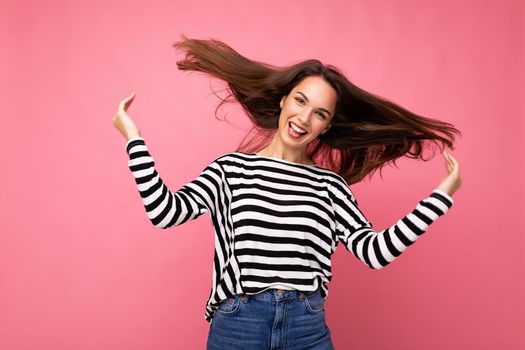 Portrait of positive cheerful fashionable woman in casual clothes isolated on pink background with copy space.