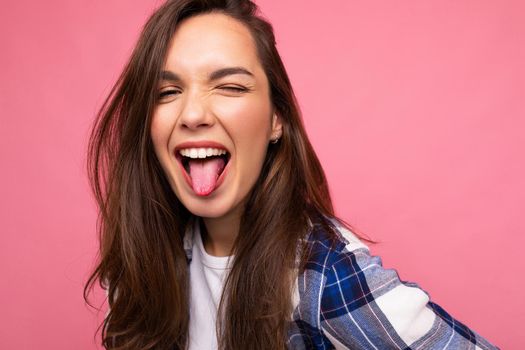 Photo shot of cute nice charming gorgeous attractive pretty youngster happy woman wearing stylish clothes isolated over colorful background with copy space showing tongue and having fun.
