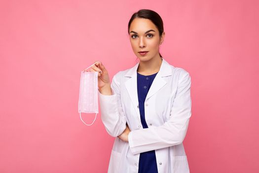 Caucasian woman showing protection face mask isolated on pink background. Coronavirus or Covid-19 Concept.