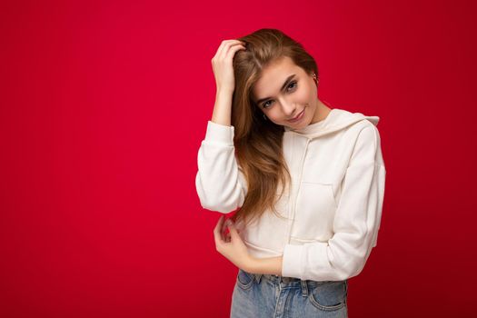 Young beautiful dark blonde woman with sincere emotions isolated on background wall with copy space wearing casual white hoodie. Positive concept.