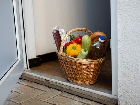 A basket filled with food, vegetables and basic necessities stands on the doorstep of the house.