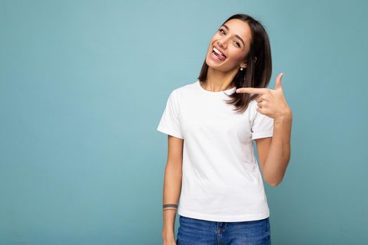 Portrait of beautiful fascinating emotional positive joyful happpy female promoter pointing to the side at copy space for advertising wearing hipster outfit isolated over background wall with empty space with sincere emotions.