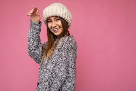 Attractive smiling happy young dark blonde woman standing isolated over colourful background wall wearing everyday stylish outfit showing facial emotions looking at camera. Empty space