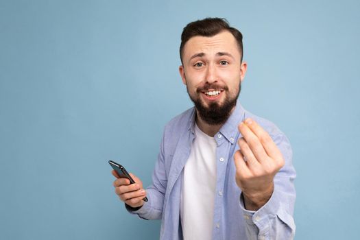 a young man with a beard on the background of a blue wall shows a gesture delicious