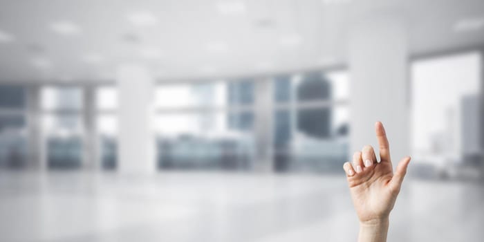 Close of woman hand touching screen with finger and office at background