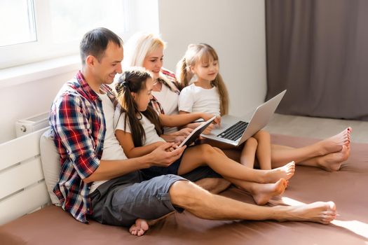 Family lying in bed using a laptop