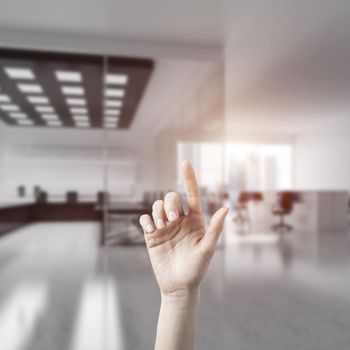 Close of woman hand touching screen with finger and office at background