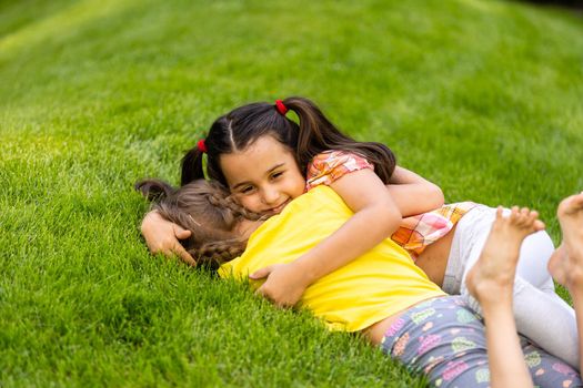 Portrait of two little girls sisters fighting on home backyard. Friends girls having fun. Lifestyle candid family moment of siblings quarreling playing together.