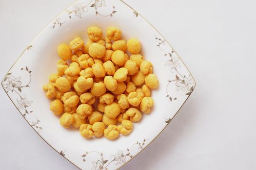 puffed corn rings chips in black bowl on white background,