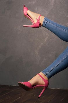 Women's legs in pink sandals with high heels in the interior.