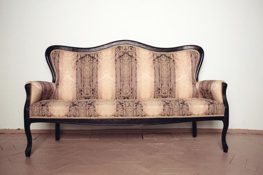 Luxurious antique velor sofa stands on a wooden floor near the wall