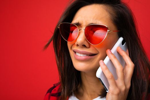 distraught girl on a red background speaks on phone, close-up.