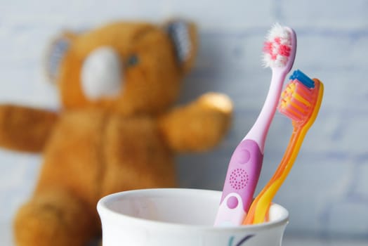 colorful toothbrushes in white mug against a wall .