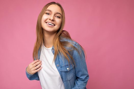 Photo shot of pretty joyful smiling young female person wearing casual trendy outfit standing isolated on colourful background with copy space looking at camera and having fun.