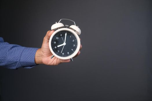 person hand holding alarm clock against gray background ,,