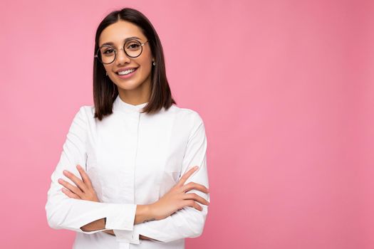 Photo shot of beautiful smiling young brunette woman wearing casual clothes and stylish optical glasses isolated over colorful background looking at camera. copy space