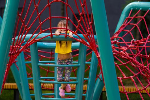 Young girls poking head through climbing rope activity using it as frame.