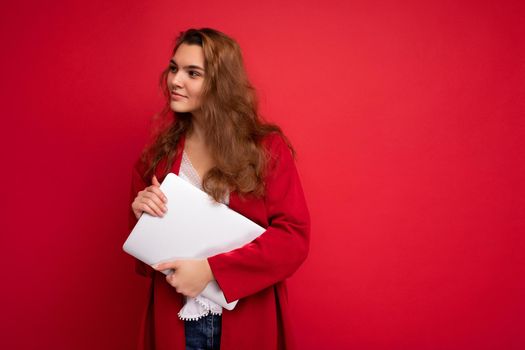 side profile photo of charming pretty young lady holding laptop isolated over wall background looking to the side and thinking over.