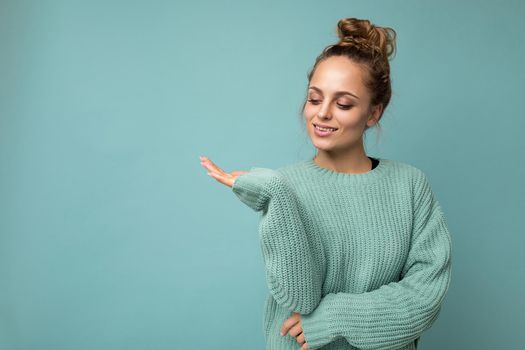 Portrait of beautiful fascinating emotional positive joyful happpy female promoter pointing to the side at copy space for advertising wearing hipster outfit isolated over background wall with empty space with sincere emotions.