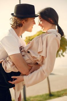 Couple by the water. Guy in a black hat. Pair on a sunset background.