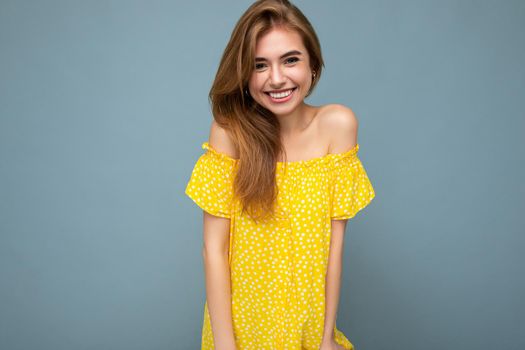 Photo of beautiful positive smiling adult woman wearing stylish clothes standing isolated on colorful background with copy space looking at camera.